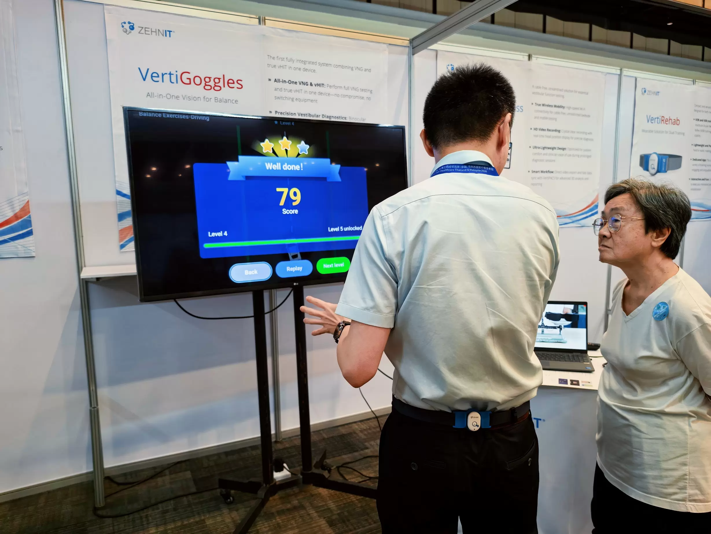 ZEHNIT team demonstrating VertiRehab balance training to a visitor at the exhibition booth.